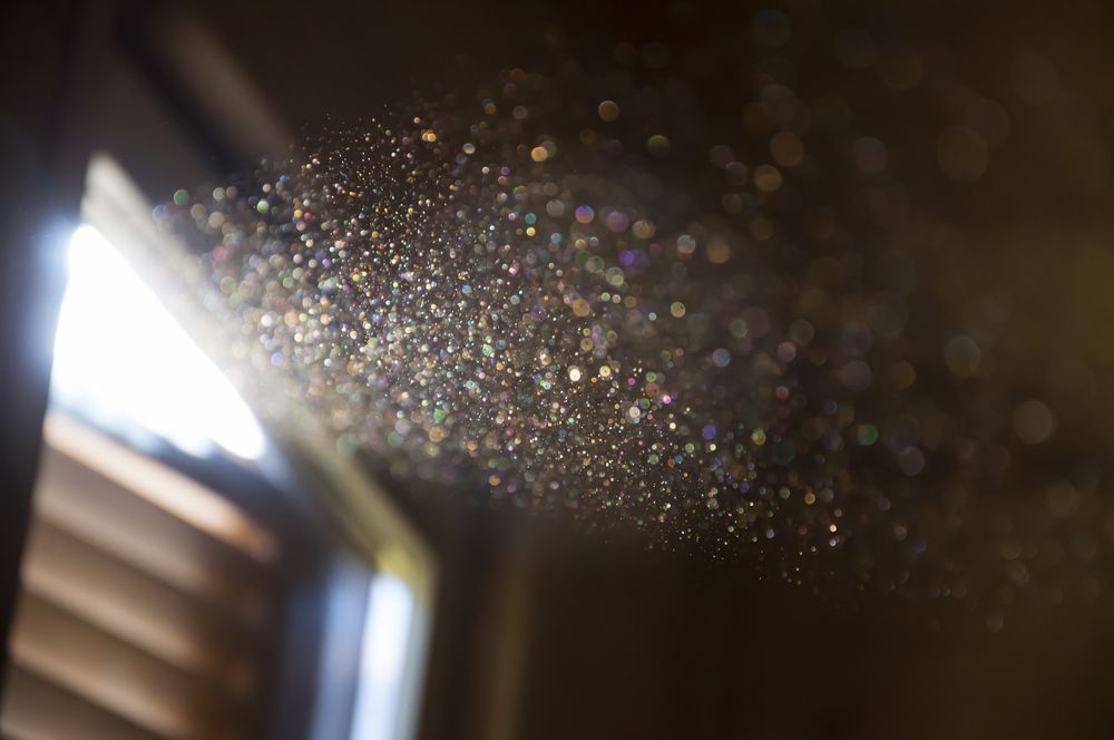 Particelle di polvere illuminate dalla luce naturale all’interno di un ambiente domestico, esempio di inquinamento dell’aria indoor.